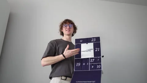 A person holding an advent calendar with numbered compartments. The calendar is  Stock Footage 301106972