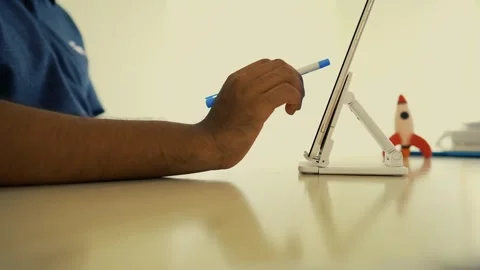 Person holding a blue pen while using a tablet on a desk, with a rocket fig.. Stock Footage 317736965