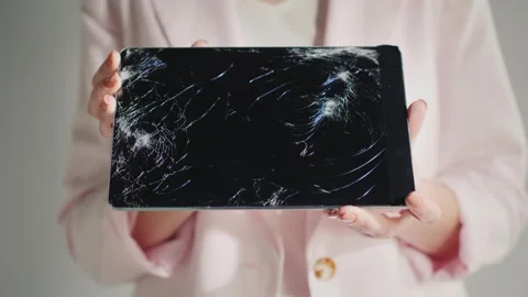 Person holding broken tablet computer with cracked screen displaying damage. Stock Footage 335026580