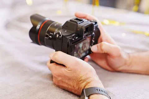 Person holding a camera while reviewing images in a cozy setting Stock Photos