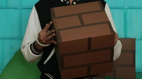 Person holding cardboard cube designed to look like brick pattern with Stock Footage 284317403