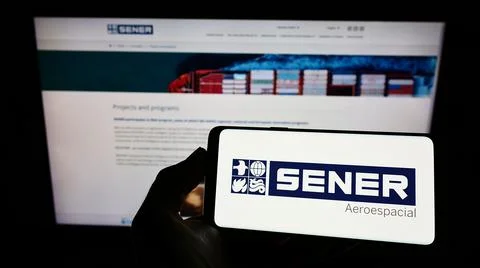 Person holding cellphone with logo of company SENER Grupo de Ingenieria SA on sc Stock Photos