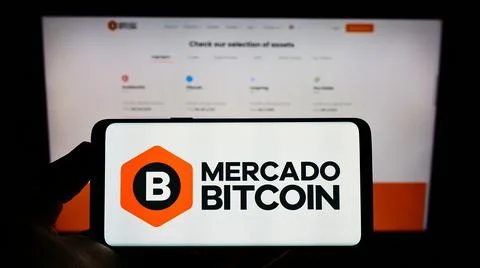 Person holding cellphone with logo of Mercado Bitcoin Servicos Digitais Ltda. on Stock Photos