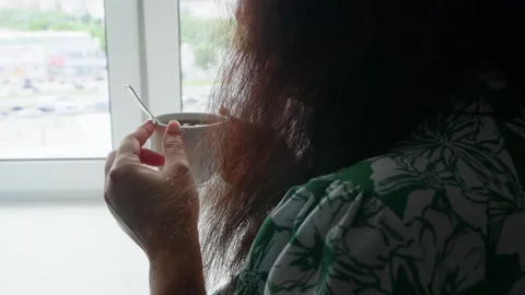 Person holding cup by window during morning routine Video stock 344516751