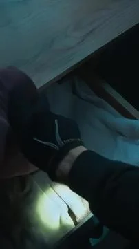 Person holding a flashlight under a desk in a dark room Stock Photos