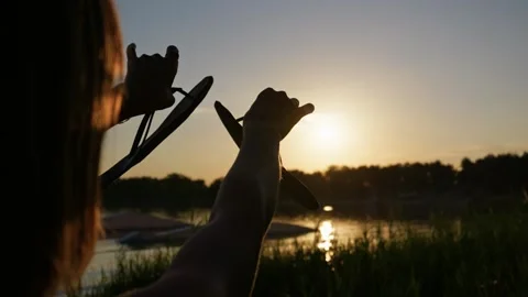 Person Holding Flip Flops Towards Golden Hour Sunset Over Lake Stock Footage 345415251