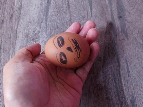 Person Holding Funny Easter Egg with Hand Drawn Face in Palm of Hand Foto stock