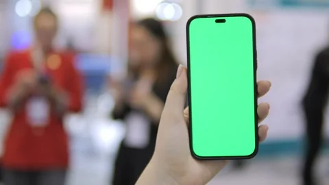 Person holding a green iPhone in front of a crowd of people Stock Footage 298943053
