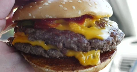 Person holding large cheeseburger with two beef patties Stock Footage 150718585