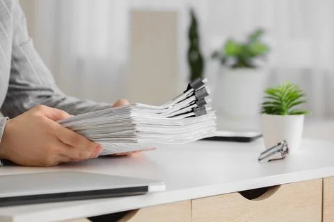 Person holding a large stack of documents with binder clips on a white office Stock Photos
