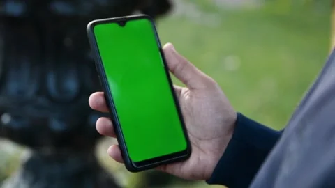 Person holding a modern looking smartphone swiping gestures outdoors vertically Stock Footage 135949953