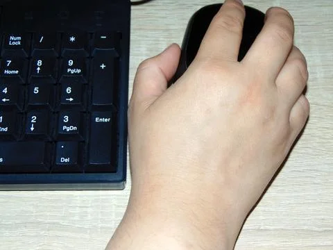 A person is holding a mouse while working on a computer Фото