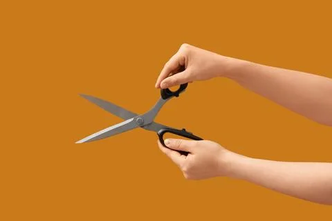 Person holding open a pair of sharp metal scissors with black handles, isolat Stock Photos
