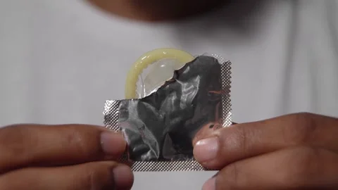 Person holding an opened condom wrapper Stock Footage 314384901