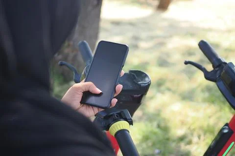Person holding a phone to scan the code of the electric scooter  for a ride in 库存照片