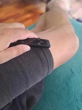 Person holding remote control while relaxing at home. Stock Photos