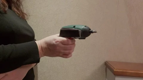 Person holding rotating screwdriver tool against wall Video stock 341559380