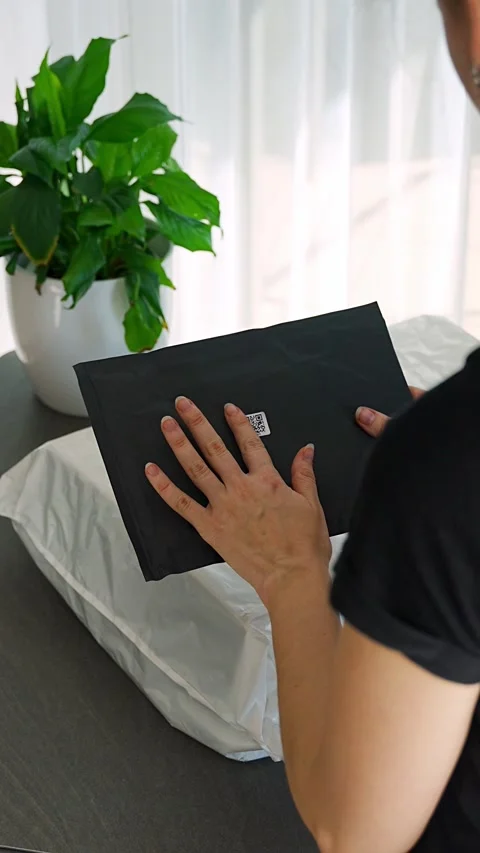 Person holding small parcel with compact QR code label compared to larger Stock Footage 345659300