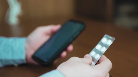 Person holding smartphone and checking prescription online with medical pil.. Vídeo Stock 340159774