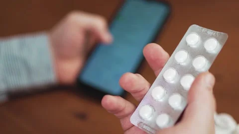 Person holding smartphone and checking prescription online with medical pil.. Stock Footage 340159830
