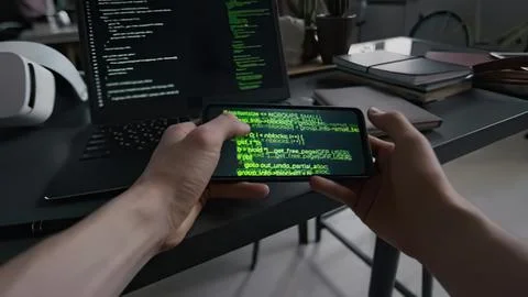 Person holding smartphone with green code on screen in office Stock Photos