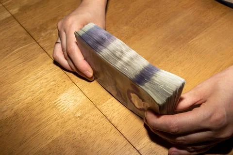 Person Holding a Stack of Cash on a Table Foto stock