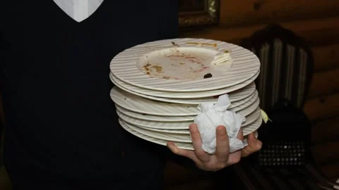 A person holding a stack of dirty plates with a tissue in their hand Stock-Footage 314979299