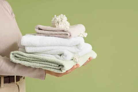 Person holding stack of folded towels with flowers Stock Photos