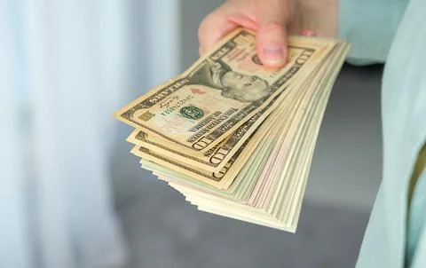 A person is holding a stack of US dollars Stock Photos