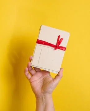 A person holding a stack of vintage postcards tied with a red ribbon and bow Stock Photos
