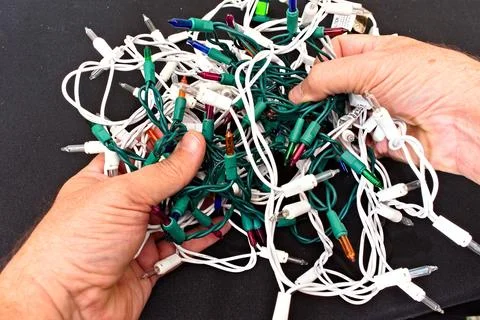 Person Holding Tangled Strings of Lights 库存照片