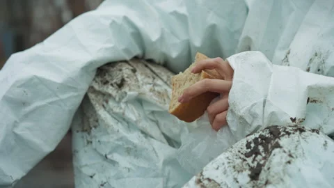 Person holding torn bread outdoors in dirty environment. An outdoor scene Stock Footage 346461602
