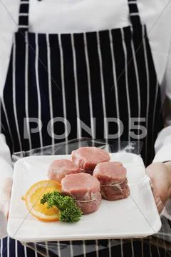 Person holding tray of pork medallions Stock Photos