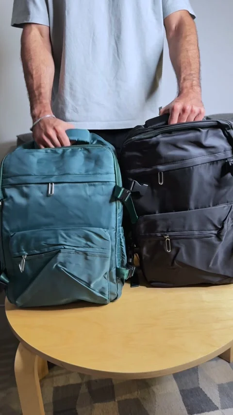 Person Holding Two Backpacks for Comparison – Blue and Black Travel Bags on Stock Footage 320222979