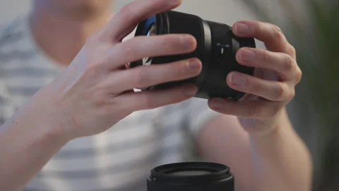 A person is holding two camera lenses, one of which is a 50mm lens Stock Footage 301620286