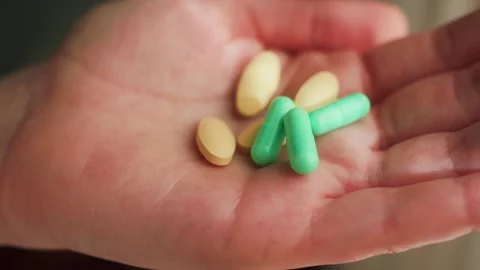 A person holding various pills of different shapes and sizes in hands. Medical Stock Footage 332592452
