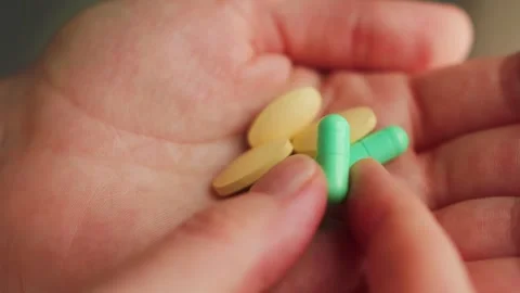 A person holding various pills of different shapes and sizes in hands. Medical Stock Footage 334138170