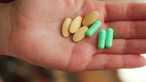 A person holding various pills of different shapes and sizes in hands. Medical Stock Footage 334537661