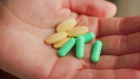 A person holding various pills of different shapes and sizes in hands. Medical Stock Footage 335774131