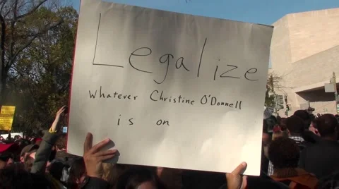 A person holds up a sign saying: