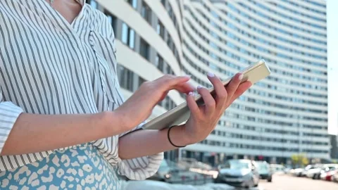 A person holds a smartphone while standing in an urban setting. They tap and 库存影片 336778358