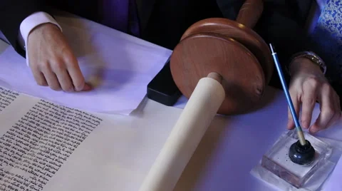 Person holds sofer hands while he completing the final letters of sefer Torah Stock Footage 66460988