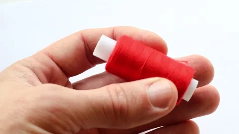 A person holds a spool of thread in their hand, a common sewing or crafting tool Stock Footage 322536016