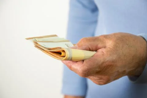 A person holds a stack of folded cash in their hands Stock Photos