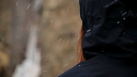 Person in hooded jacket outdoors with falling snow Stock Footage 345840612