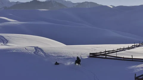 Person horseback riding pulling someone on a snow tube Stock Footage 320742508
