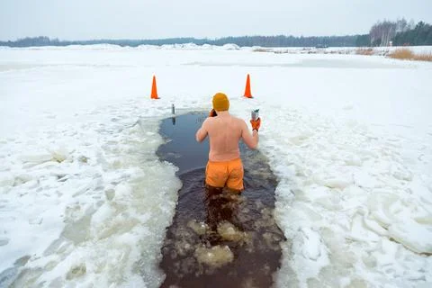 Person Ice Bathing in Snowy Landscape with Traffic Cones Nearby Stock Photos