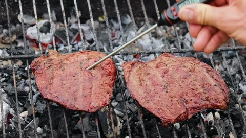 Person inserting meat thermometer into steak on a barbecue grill Stock Footage 295058723