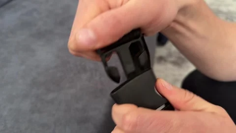 A person inserts and removes a small black plastic buckle using both hands Stock Footage 335074468