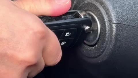 A person inserts a car key into the ignition, ready to start the engine Stock Footage 291393040